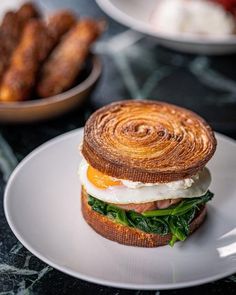 there is a sandwich on the plate with egg and spinach in the middle, along with other food items