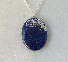 This pendant features delicate silver leaf work on a natural stone. The metal is treated with a micro-crystalline wax to preserve and protect the silver work. The chain measures 18 inches. The pendant is approximately 30 x 40 mm. Silver Lapis Lazuli Round Pendant Necklace, Silver Lapis Lazuli Gemstone Necklace, Silver Necklace With Round Lapis Lazuli Pendant, Oval Pendant Lapis Lazuli Jewelry Gift, Oval Lapis Lazuli Silver Jewelry, Oval Silver Lapis Lazuli Jewelry, Silver Jewelry With Oval Lapis Lazuli, Silver Lapis Lazuli Round Pendant Jewelry, Silver Nature-inspired Jewelry With Large Stone