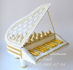 a cake shaped like a piano with gold decorations on it's top and sides