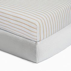 the bottom half of a bed with a white and brown striped cover