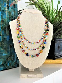 "I made this fun and colorful beaded necklace, with multi strands of glass seed beads, in a rainbow of colors. The larger glass beads on the longest strand, are made with multi colored evil eye beads, and multi colored millefiori beads. This necklace has 3 strands of colorful beads. Add color and get noticed, with this statement necklace for women who are fun and colorful. This colorful necklace is 24 inches long, and has a 2\" extension chain. This necklace is ready to send to you today, and in Colorful Fun Beaded Necklaces With Round Beads, Fun Multicolor Beaded Necklaces For Beach, Multicolor Round Beads Necklace - Fun Style, Colorful Fun Round Beaded Necklaces, Multicolor Fun Beaded Necklace, Fun Multicolor Round Beads Necklace, Fun Multicolor Beaded Necklace, Fun Multicolor Handmade Beads, Rainbow Multi-strand Beaded Necklaces