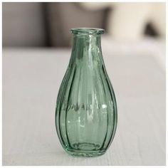 a green vase sitting on top of a white table