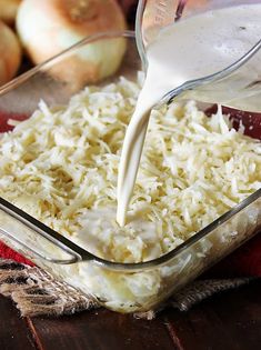 someone pouring milk into a casserole dish with onions in the background