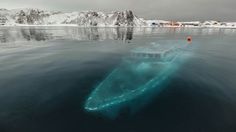 a boat floating on top of a body of water next to snow covered mountains in the distance