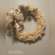 a christmas wreath hanging on the wall with pine cones and ornaments around it's edges