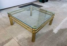 a glass and gold coffee table sitting on the ground in front of a garage door