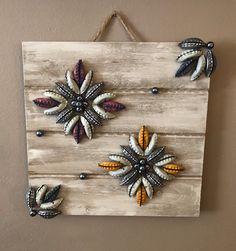 a wooden sign hanging on the side of a wall with beaded flowers attached to it