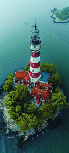 an island with a lighthouse on it in the middle of the ocean, surrounded by trees