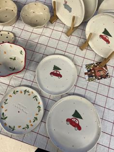 several plates and bowls with christmas designs on them are sitting on a tablecloth covered surface