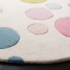 a rug with multi colored dots on it sitting on top of a wooden floor next to a black table