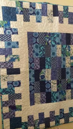 a blue and white quilt hanging on the wall