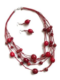 Red Tagua Bib Necklace Ecuadorean Tagua Jewelry - Eco Friendly Part Number: TAG707 Item Weight: 1.15oz Product Length: 24 inches long Earrings Length: 2 inches About Tagua This Product is handcrafted from a palm tree nut native to the lush tropical rainforests of Ecuador. Also referred to as the Ecuadorean Ivory Palm, the Tagua tree produces several bushels of seed pods a year with up to 100 Tagua nuts per pod. These nuts are then harvested, dried, and crafted into a wide range of products from Multi-strand Necklace With Red Wooden Beads, Multi-strand Red Necklace With Wooden Beads, Red Multi-strand Necklace With Wooden Beads, Red Wooden Beads Round Necklace, Red Wooden Beads Jewelry As A Gift, Red Wooden Beads Jewelry For Gift, Red Wooden Beads Jewelry Gift, Red Necklace With Wooden Beads, Red Beaded Dangle Necklace