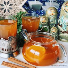 there is a tea pot and two cups on the table with cinnamon sticks next to it