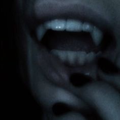 a person with their mouth open in the dark, showing it's teeth and tongue