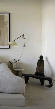 a bedroom with white walls and an art work on the wall