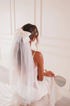 a woman in a wedding dress sitting on the floor looking at her reflection in a mirror