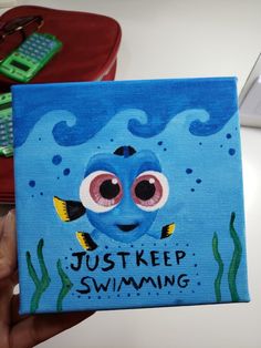 a painting of a blue fish with the words just keep swimming on it's face