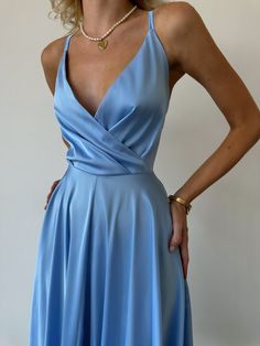 a woman in a blue dress posing for the camera with her hands on her hips