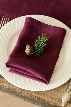 a napkin with a pine cone on it sits on a plate next to a fork and knife