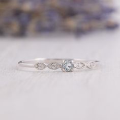 a white gold engagement ring with an aqua blue diamond and two diamonds on the band