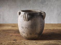 a gray vase sitting on top of a wooden table