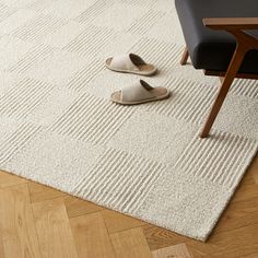 a pair of slippers sitting on top of a white rug next to a chair