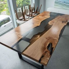 a table made out of wood and glass in a room with large windows overlooking the ocean