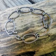 This silver chain bracelet was made with Argentium Silver square wire that was formed into oval shapes and textured on both sides. The organically shaped links were connected to each other with 2 jump rings made of Argentium Silver wire. The handcrafted hook is also Argentium Silver wire. The finished bracelet was oxidized to enhance the textured marks and then polished to reveal the silver. Sterling Silver Bracelet With Oval Links, Handmade Metal Chain Bracelet With Rectangular Links, Handmade Chain Bracelet With Rectangular Metal Links, Adjustable Silver Chain Bracelet With Oval Links, Adjustable Oval Link Silver Chain Bracelet, Adjustable Oval Link Sterling Silver Bracelet, Handmade Adjustable Oval Link Chain Bracelet, Silver Oval Link Chain Bracelet With Hook, Metal Link Bracelets With Oxidized Finish