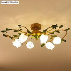 a chandelier hanging from the ceiling with white flowers and green leaves on it