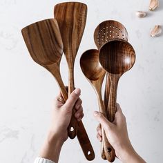 wooden utensils are being held by two hands