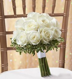 a bouquet of white roses sitting on top of a chair