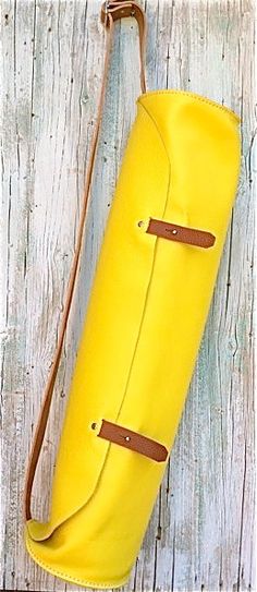 a yellow leather bag sitting on top of a wooden table next to a white wall