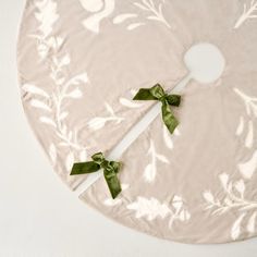 two green bows are tied to the side of a round tablecloth on a white surface