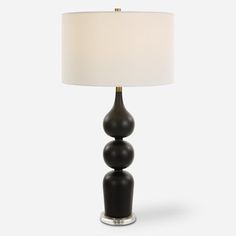 a black lamp with a white shade on the top and two balls on the bottom