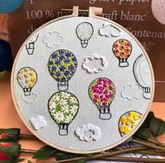 an embroidery project with hot air balloons and flowers on the hoop, surrounded by other items