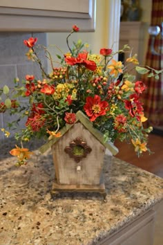 a birdhouse filled with flowers on top of a counter