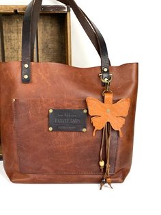 a brown leather bag with a butterfly on it