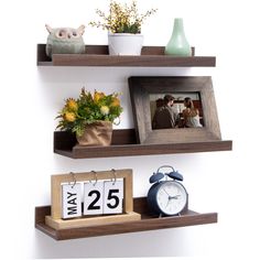 two wooden shelves with pictures, flowers and an alarm clock