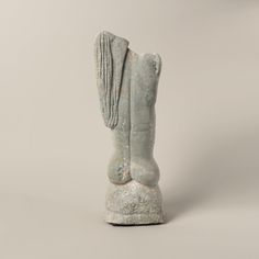 an old statue is sitting on a white surface and it appears to be in the shape of a boot