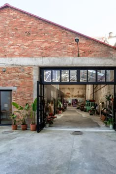 an open garage door with potted plants on the outside and brick building in the background