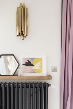 a radiator and some pictures on a shelf in a room with pink curtains