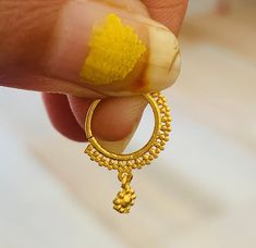 a hand holding a gold ring with a yellow substance on it's side and the end of its finger