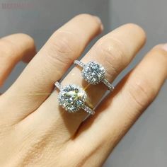 two diamond engagement rings sitting on top of someone's hand in front of a mirror