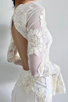 the back of a woman's white dress with flowers on it and sheer sleeves