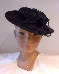 "Here's a dashing hat with great Art Deco trim. An original late 1930s day hat, its in dark navy blue faux straw, with navy velvet and grosgrain trims. A charming tilt hat, the circular crown is shallow, with a medium width brim; a slim velvet ribbon serves as a hat band. Perched to the left of the front is a dramatic oversized pinwheel trim, with a velvet centre holding a quartet of sharply geometric grosgrain tabs spreading onto the crown and over to the edge of the brim, with fine blue cord p Victorian Evening Hats For Kentucky Derby, Navy Formal Hat With Curved Brim, Navy Curved Brim Formal Hat, Vintage Wide Brim Felt Hat For Evening, Vintage Fitted Felt Hat For Evening, Vintage Navy Hat With Curved Brim, Vintage Curved Brim Felt Hat For Evening, Vintage Fitted Straw Hat For Formal Occasions, Vintage Felt Hat With Curved Brim For Evening