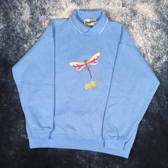 "Details: Vintage baby blue dragonfly embroidered collared sweatshirt by Ramblers. Condition: New with tags Signs of wear: N/A Size: Tag states Large but fit is like a Small Measurements: Length - 25\" Pit to Pit - 22\" Shoulder to cuff - 19.5\"" Blue Ribbed Collar Sweatshirt For Spring, Spring Collared Cotton Sweatshirt, Spring Cotton Collared Sweatshirt, Casual Collared Sweatshirt For Spring, Vintage Blue Sweatshirt For Spring, Blue Dragonfly, Collared Sweatshirt, Zip Sweatshirt, Vintage Baby