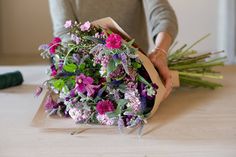 a woman holding a bouquet of flowers on top of a table