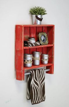 a red wooden shelf with some jars on top of it and a potted plant in the corner