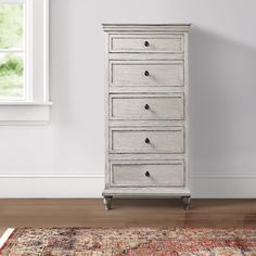 a white chest of drawers sitting on top of a wooden floor next to a window