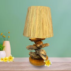 a lamp sitting on top of a wooden table next to a vase with yellow flowers